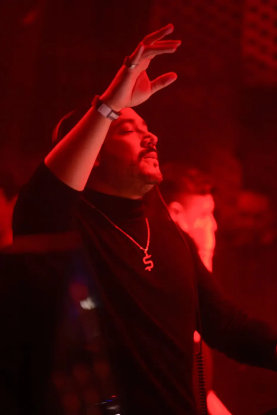 Shant con el brazo en alto bajo luces rojas